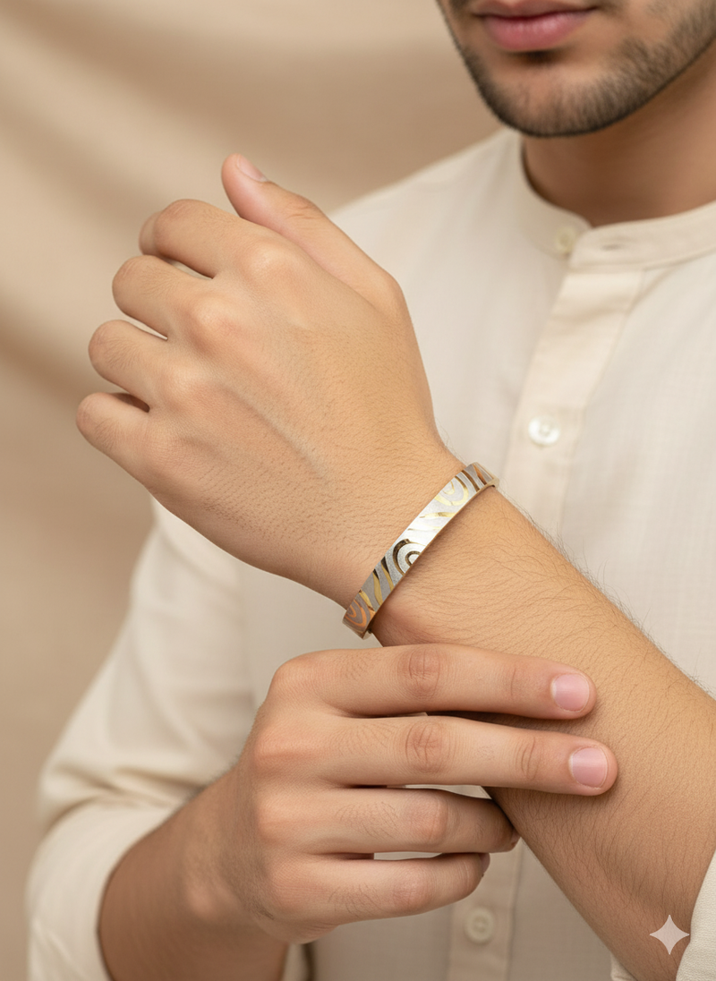 Person wearing a Aura Bling gold bracelet with a pattern design on a neutral background