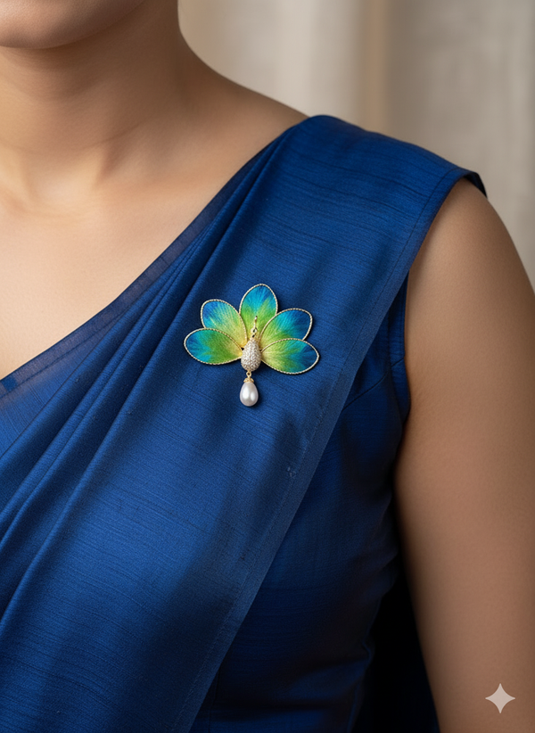 Close-up of green and blue threadwork fabric peacock bloom brooch with stone centre and pearl drop pinned on saree