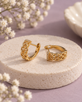 Everyday Interlace Hoops with gold-tone interwoven links and clear stone accents on an ivory pedestal