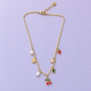 The Charm Diary Necklace with seven assorted charms on a lavender background