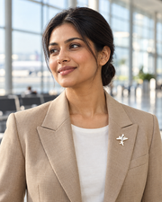 Wanderwing Brooch worn as a small airplane pin on a female model's beige blazer in an airport